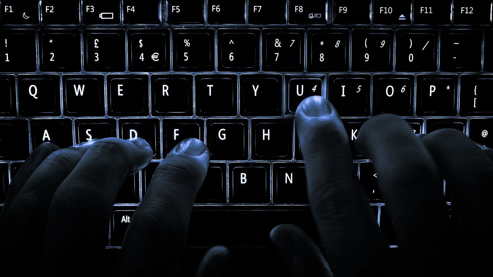 A backlit laptop keyboard photographed in low light.