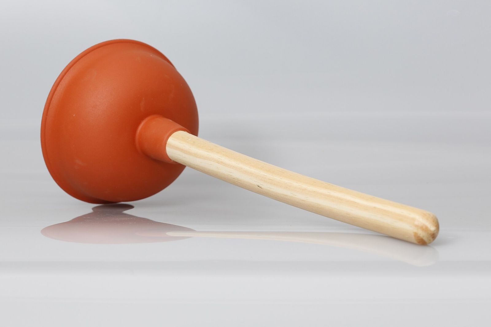 A rubber cup plunger with a wooden handle.