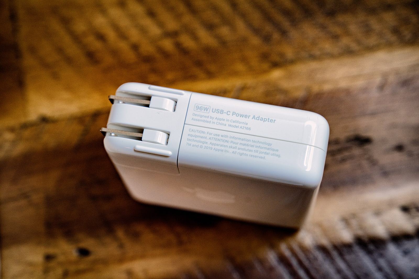 A 96-watt USB-C power adapter resting on a wooden surface.